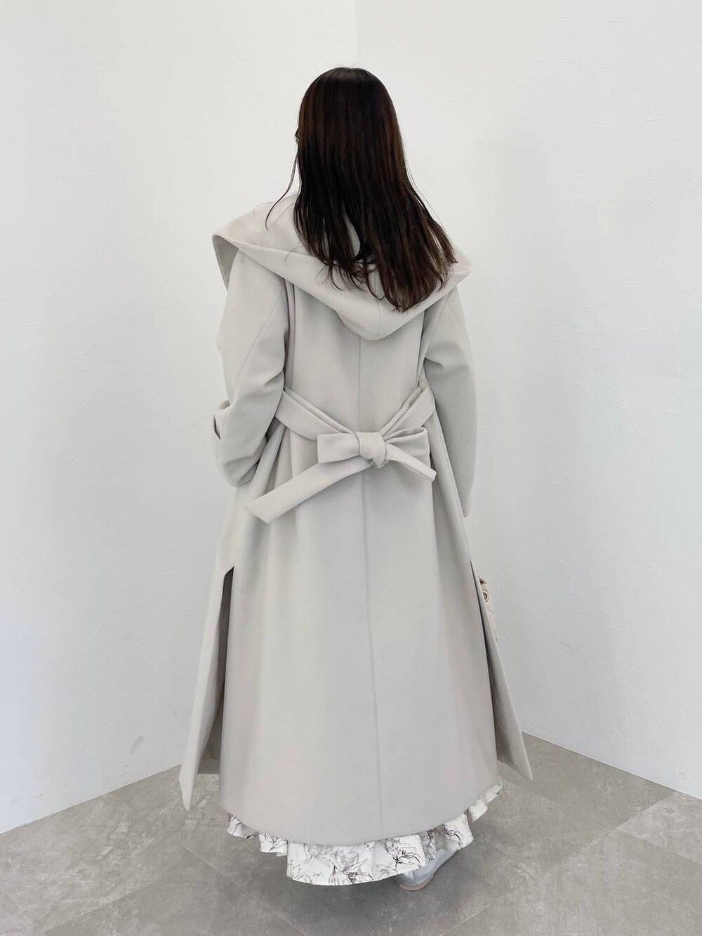 パープル系のニット/セーター、ホワイト系のショルダーバッグ、ホワイト系のノーカラーコートを着用したレディースの冬コーディネートの2枚目の写真