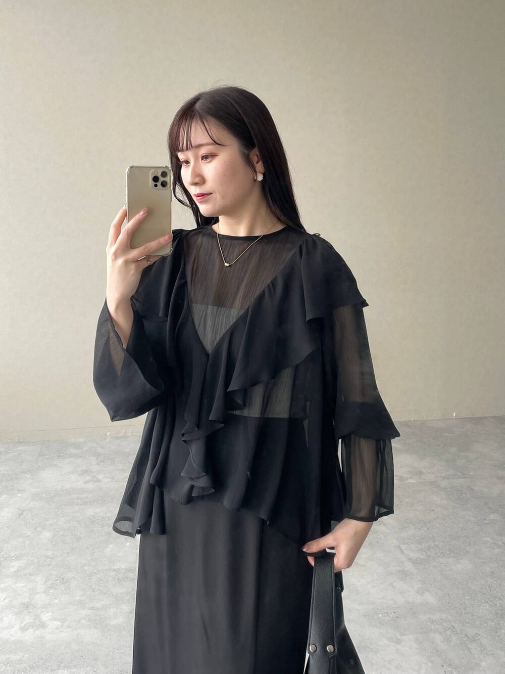 ブラック系のスカート、ブラック系のローファー、ブラック系のショルダーバッグを着用したレディースの春コーディネートの3枚目の写真