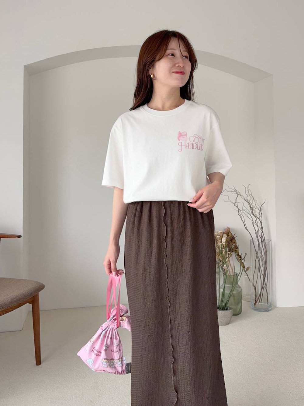 ブラウン系のスカート、ホワイト系のTシャツ/カットソー、ホワイト系のサンダルを着用したレディースの夏コーディネートの3枚目の写真