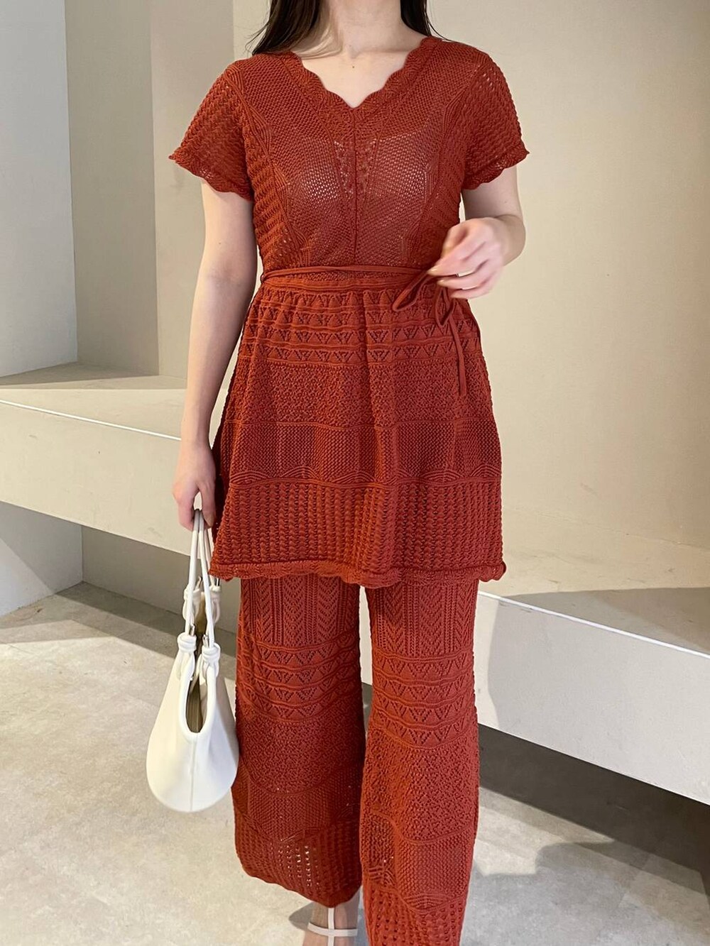 ホワイト系のハンドバッグ、オレンジ系のニット/セーター、ホワイト系のサンダルを着用したレディースの春コーディネートの5枚目の写真