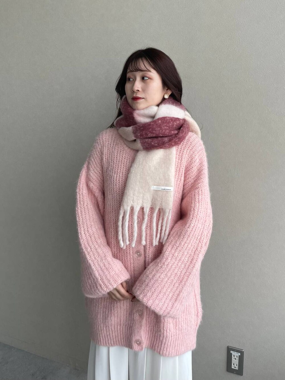 ブラウン系のブーツ、ピンク系のカーディガン/ボレロ、ブラウン系のハンドバッグを着用したレディースの秋コーディネートの4枚目の写真