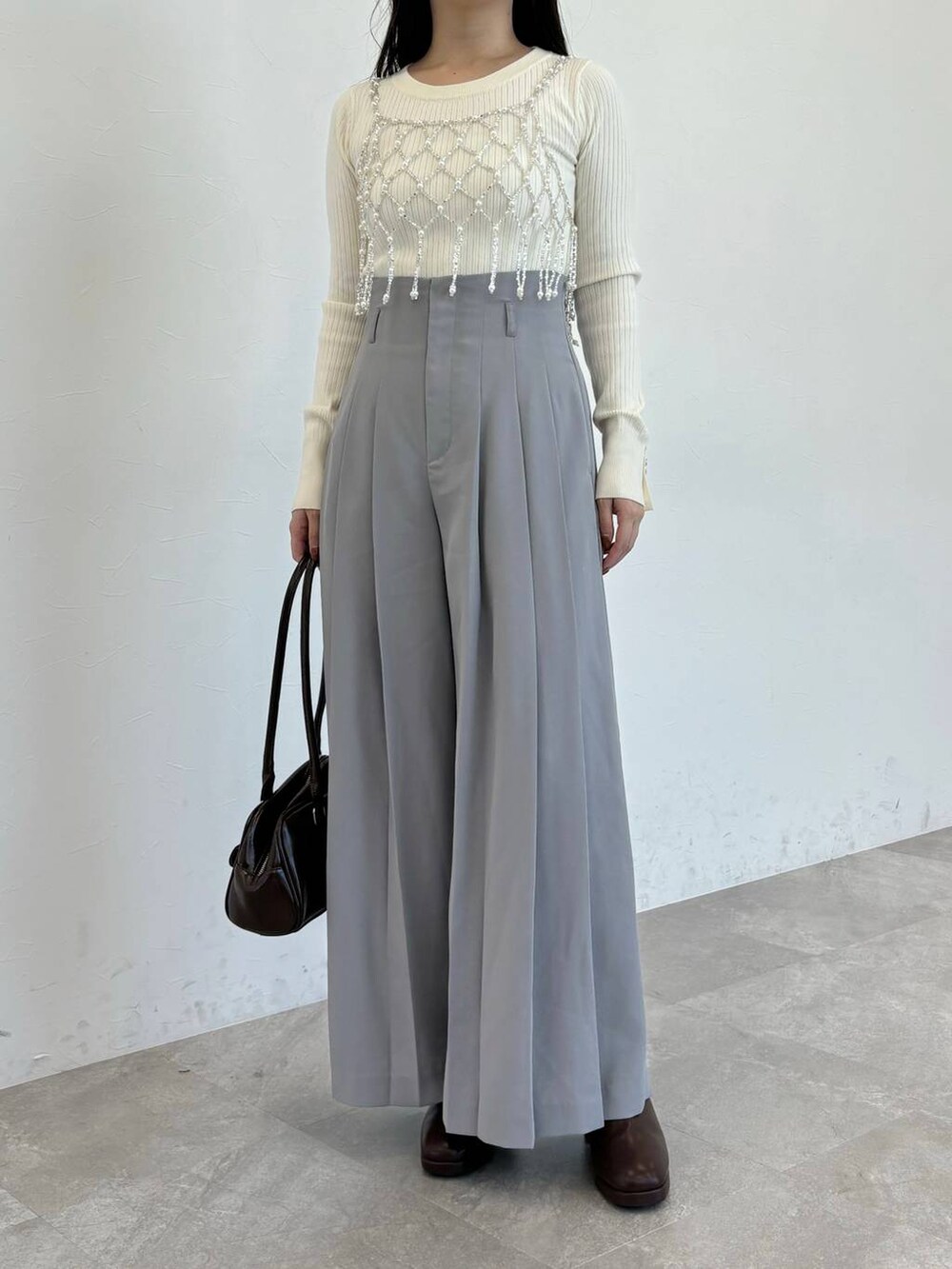 ブラウン系のブーツ、ホワイト系のニット/セーター、ブラウン系のハンドバッグを着用したレディースの冬コーディネートの4枚目の写真