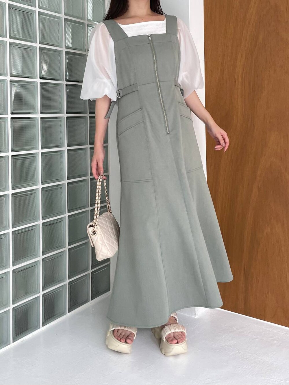 グリーン系のジャンパースカート、ホワイト系のショルダーバッグ、ホワイト系のサンダルを着用したレディースの夏コーディネートの3枚目の写真