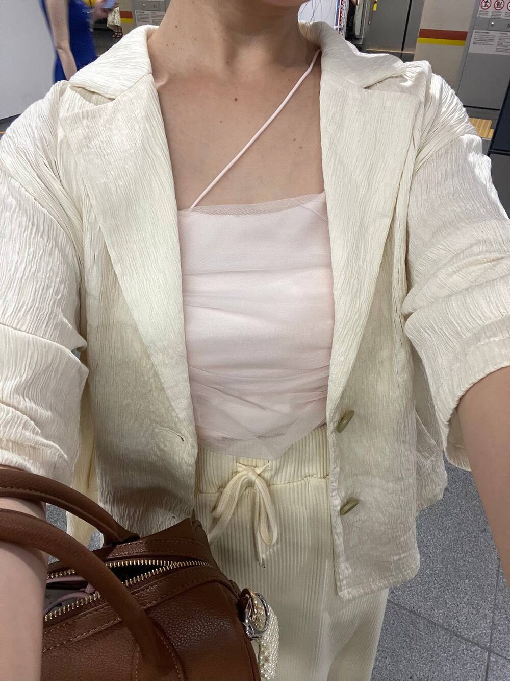 ホワイト系のスカート、ホワイト系のテーラードジャケット、ブラウン系のショルダーバッグを着用したレディースの夏コーディネートの4枚目の写真