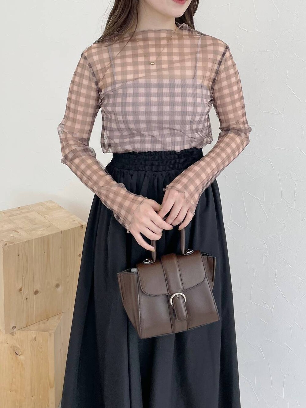 ブラック系のスカート、ブラウン系のハンドバッグ、ブラック系のパンプスを着用したレディースの秋コーディネートの4枚目の写真