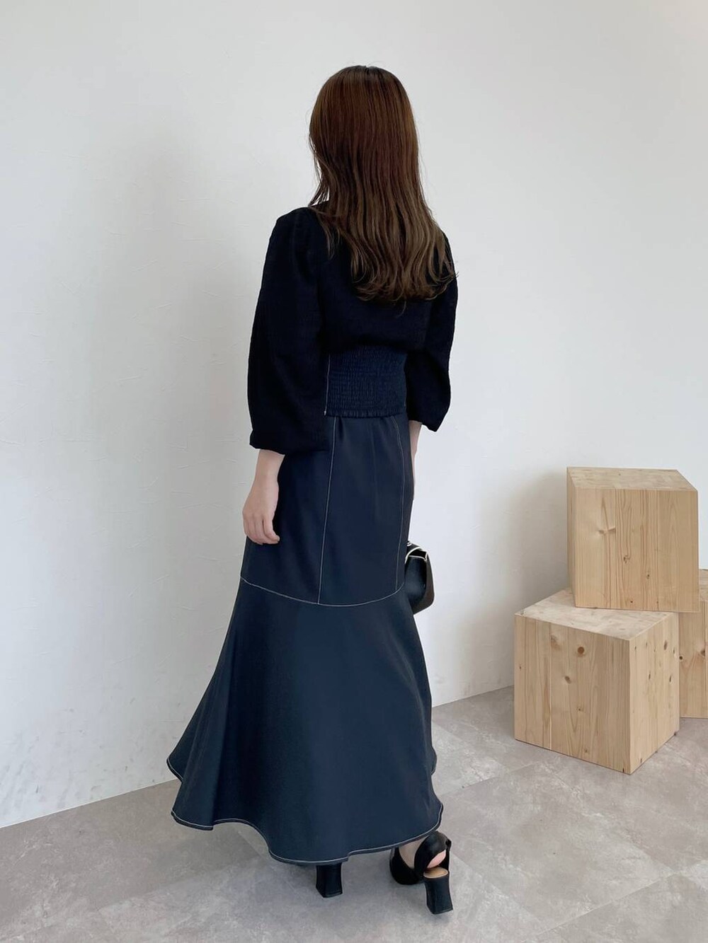 ブラック系のハンドバッグ、グレー系のスカート、ブラック系のパンプスを着用したレディースの夏コーディネートの2枚目の写真