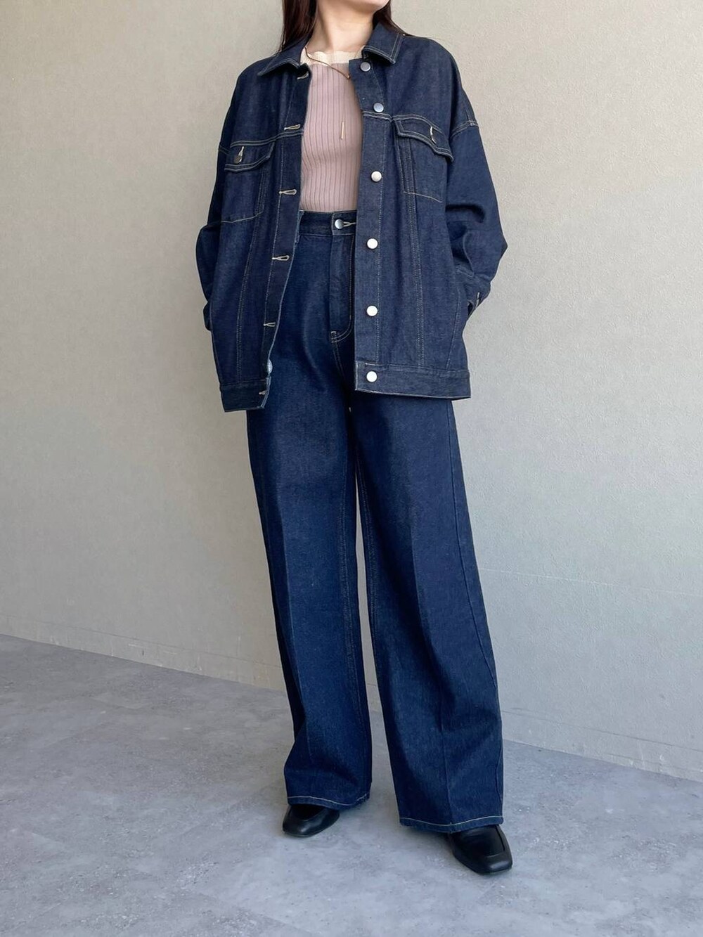 ブラック系のショルダーバッグ、ブルー系のデニムパンツ、ベージュ系のニット/セーターを着用したレディースの冬コーディネートの4枚目の写真