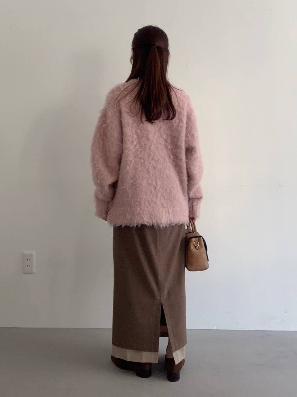 ブラウン系のローファー、ブラウン系のショルダーバッグ、ベージュ系のスカートを着用したレディースの冬コーディネートの2枚目の写真