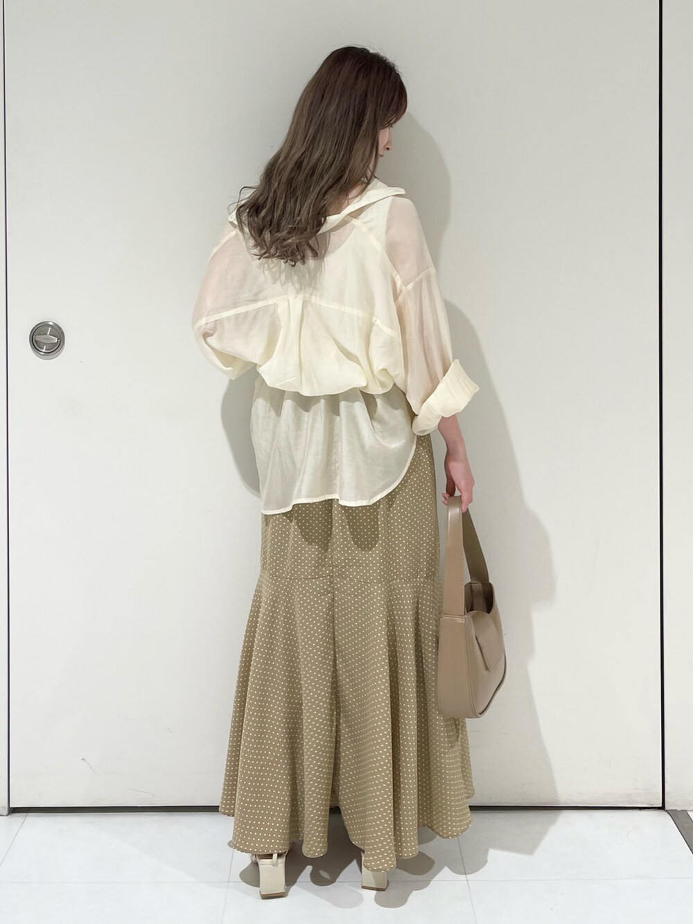 ホワイト系のシャツ/ブラウス、ベージュ系のスカート、ブラウン系のハンドバッグを着用したレディースの夏コーディネートの2枚目の写真