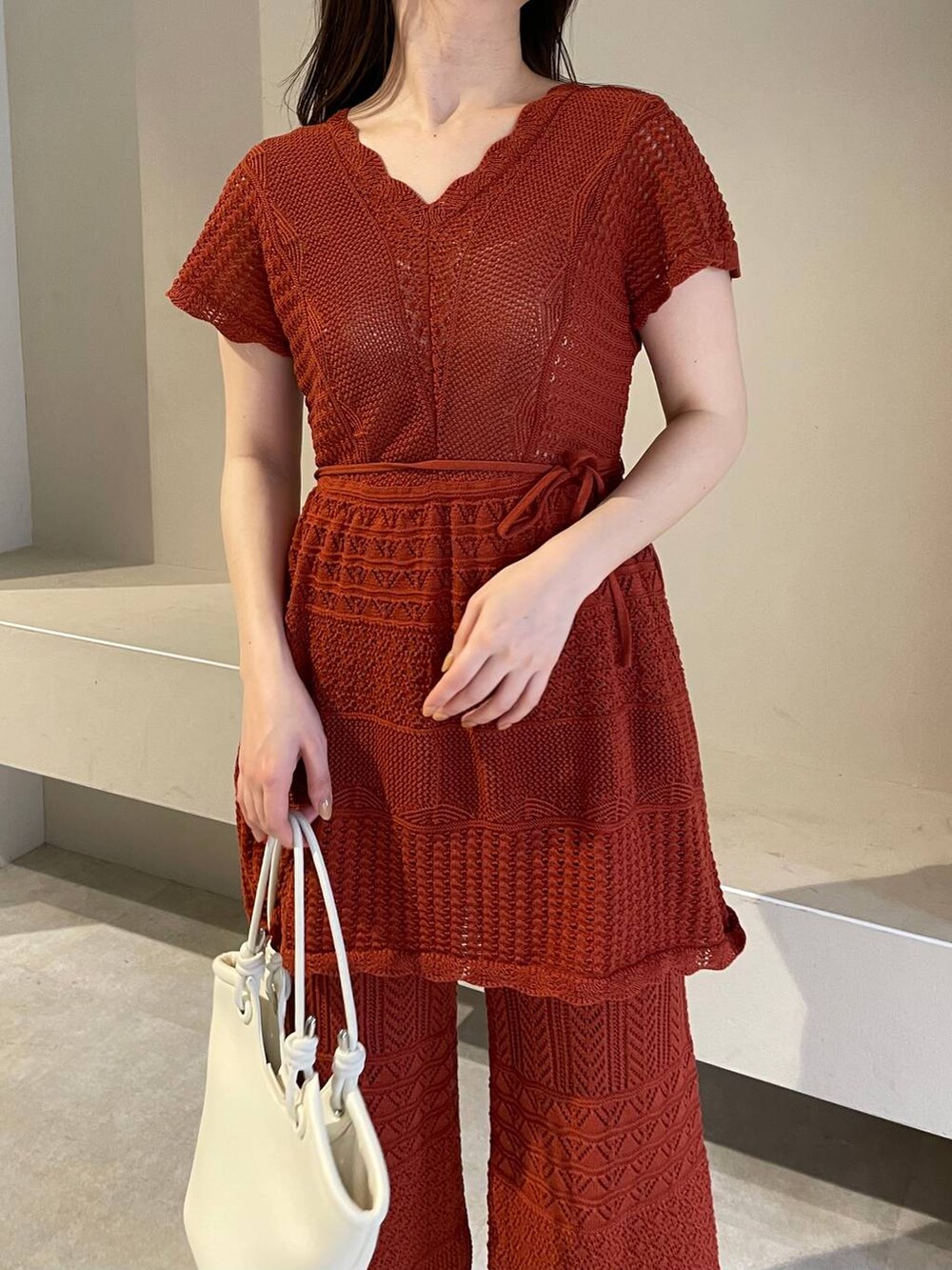 ホワイト系のハンドバッグ、オレンジ系のニット/セーター、ホワイト系のサンダルを着用したレディースの春コーディネートの4枚目の写真