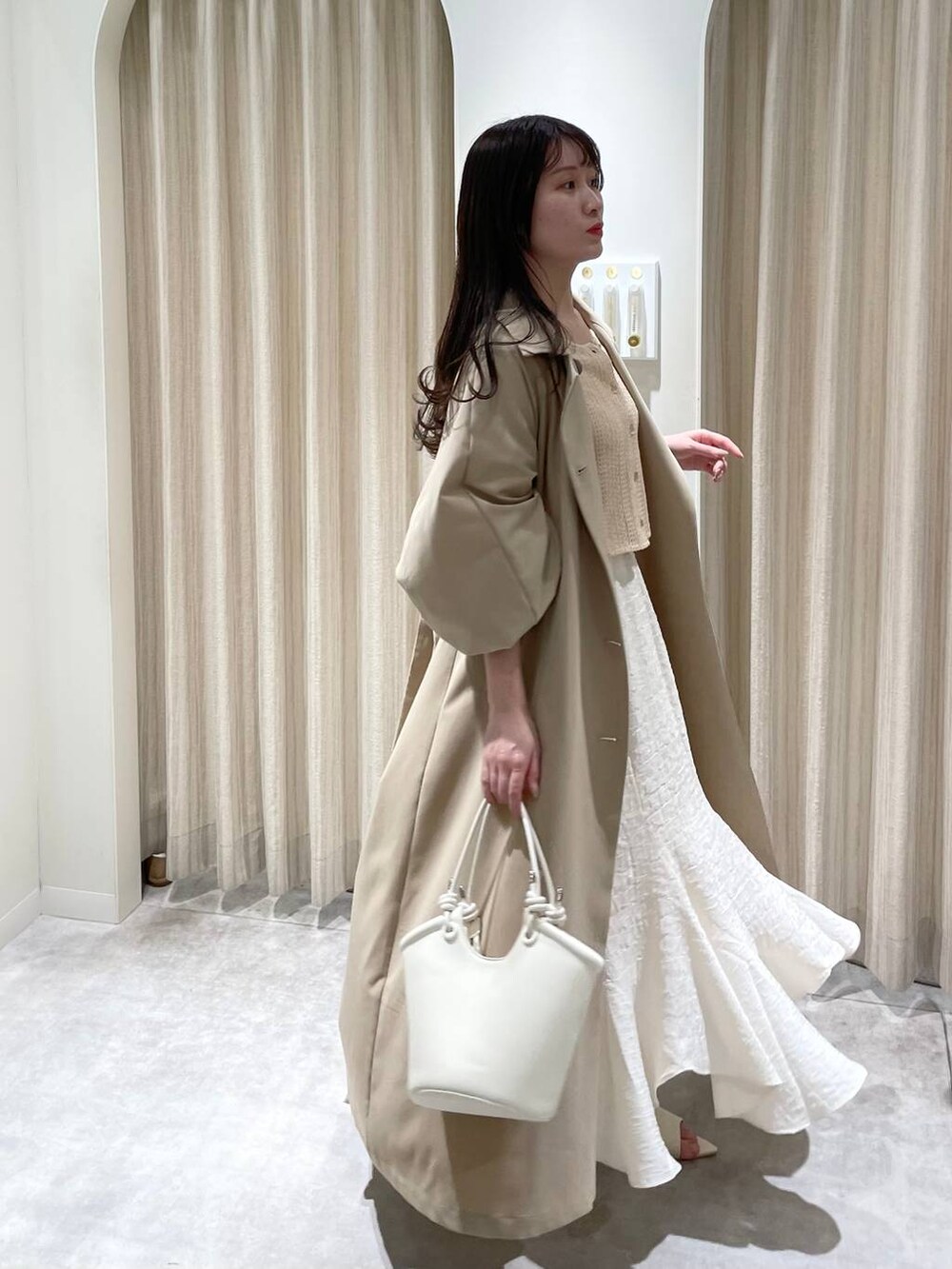 ベージュ系のTシャツ/カットソー、ホワイト系のハンドバッグ、ホワイト系のブーツを着用したレディースの春コーディネートの3枚目の写真