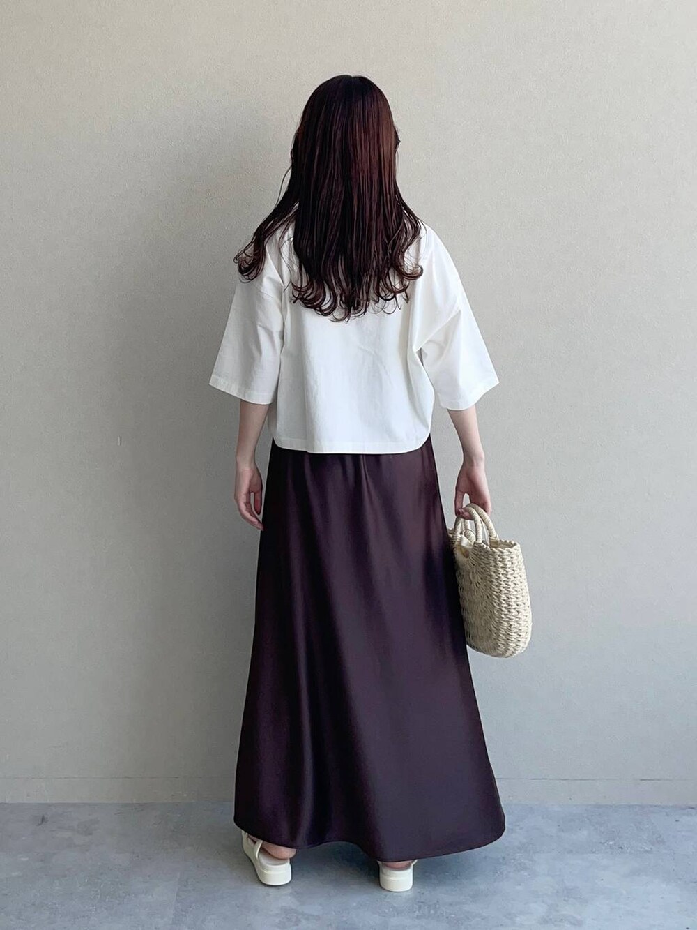 ブラウン系のスカート、ホワイト系のTシャツ/カットソー、ベージュ系のかごバッグを着用したレディースの春コーディネートの2枚目の写真