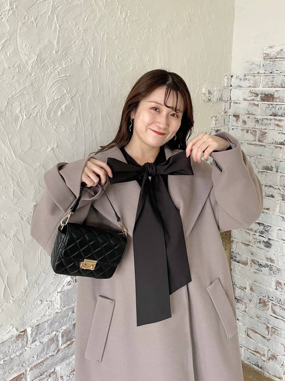 グレー系のノーカラーコート、ブラック系のブーツ、ブラック系のニット/セーターを着用したレディースの秋コーディネートの3枚目の写真