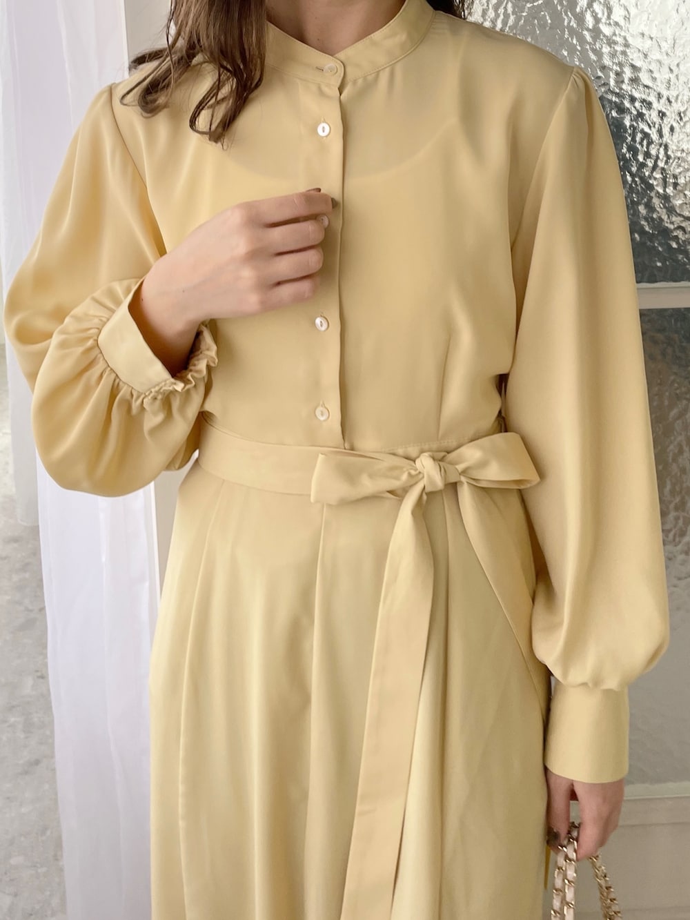 イエロー系のワンピース、ホワイト系のバッグ、ホワイト系のブーツを着用したレディースの冬コーディネートの3枚目の写真