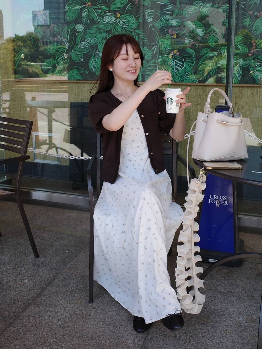 ブラウン系のカーディガン/ボレロ、ホワイト系のワンピース、ホワイト系のスマホグッズを着用したレディースの夏コーディネートの2枚目の写真