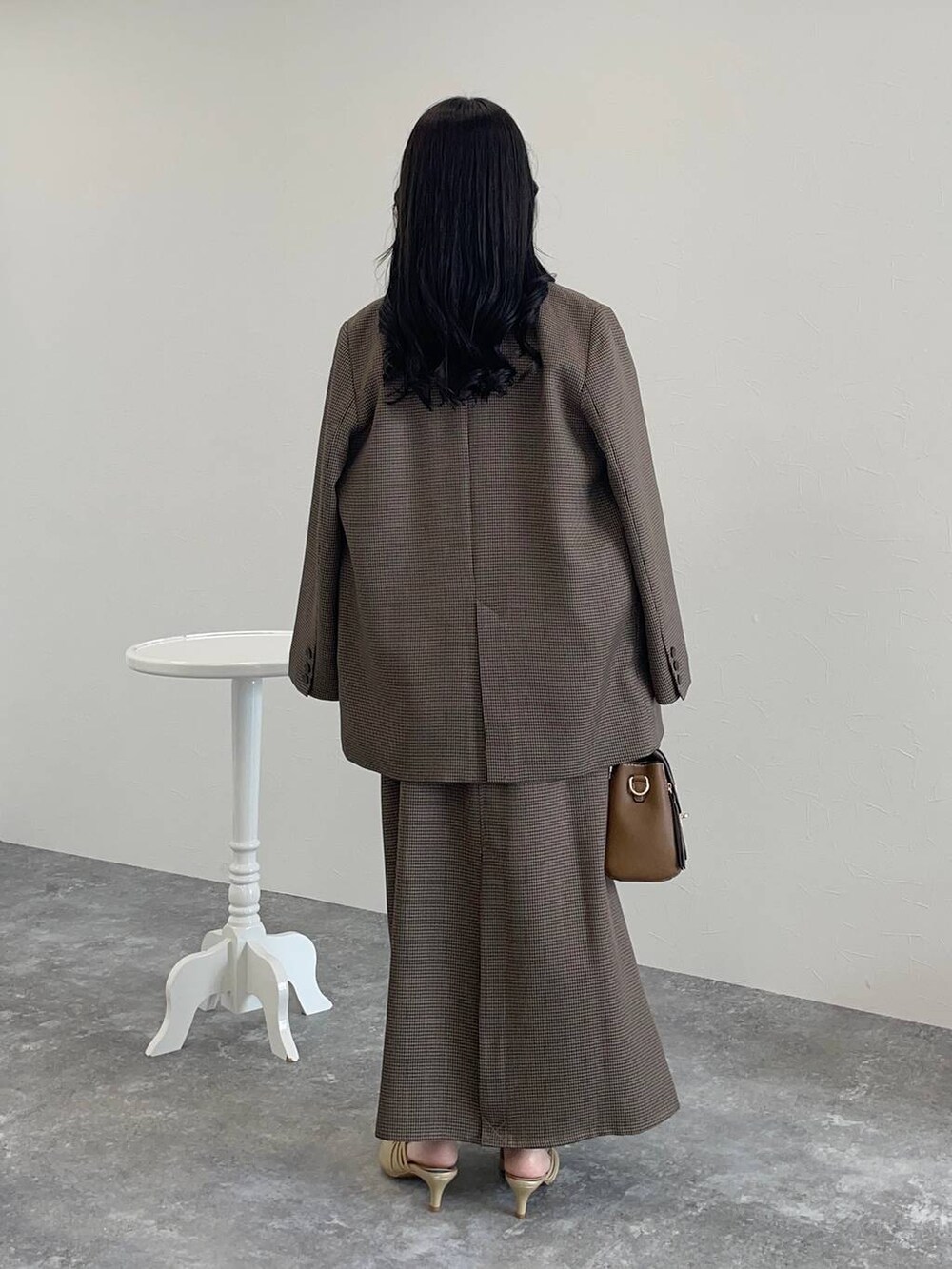 ゴールド系のパンプス、ブラウン系のショルダーバッグ、ホワイト系のシャツ/ブラウスを着用したレディースの秋コーディネートの2枚目の写真