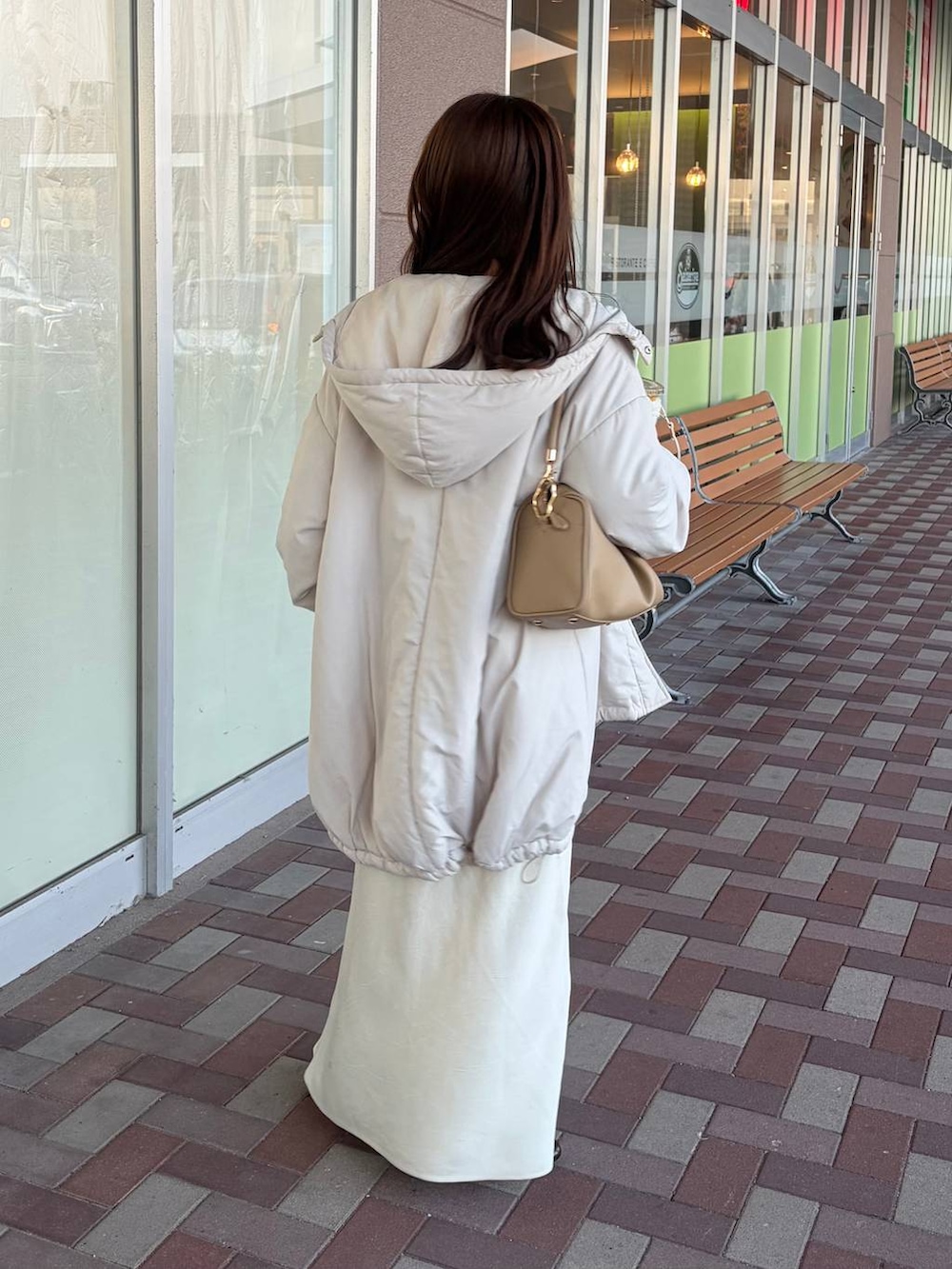 ホワイト系のスカート、ゴールド系のボストンバッグ、ブラウン系のカーディガン/ボレロを着用したレディースの冬コーディネートの2枚目の写真