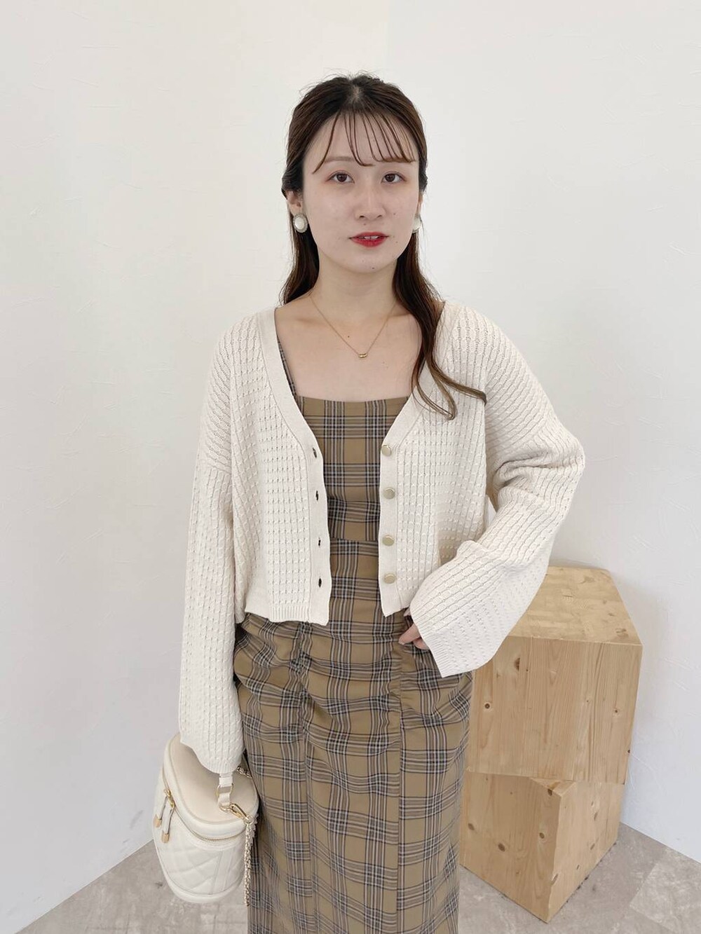 ホワイト系のカーディガン/ボレロ、ホワイト系のパンプス、ベージュ系のジャンパースカートを着用したレディースの夏コーディネートの3枚目の写真