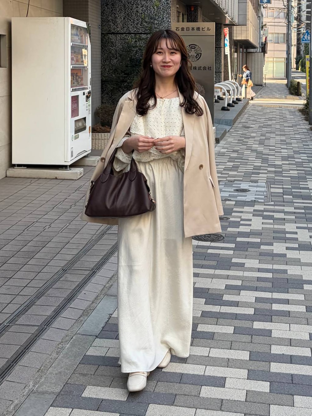 ホワイト系のスカート、ブラウン系のボストンバッグ、ベージュ系のテーラードジャケットを着用したレディースの春コーディネートの2枚目の写真