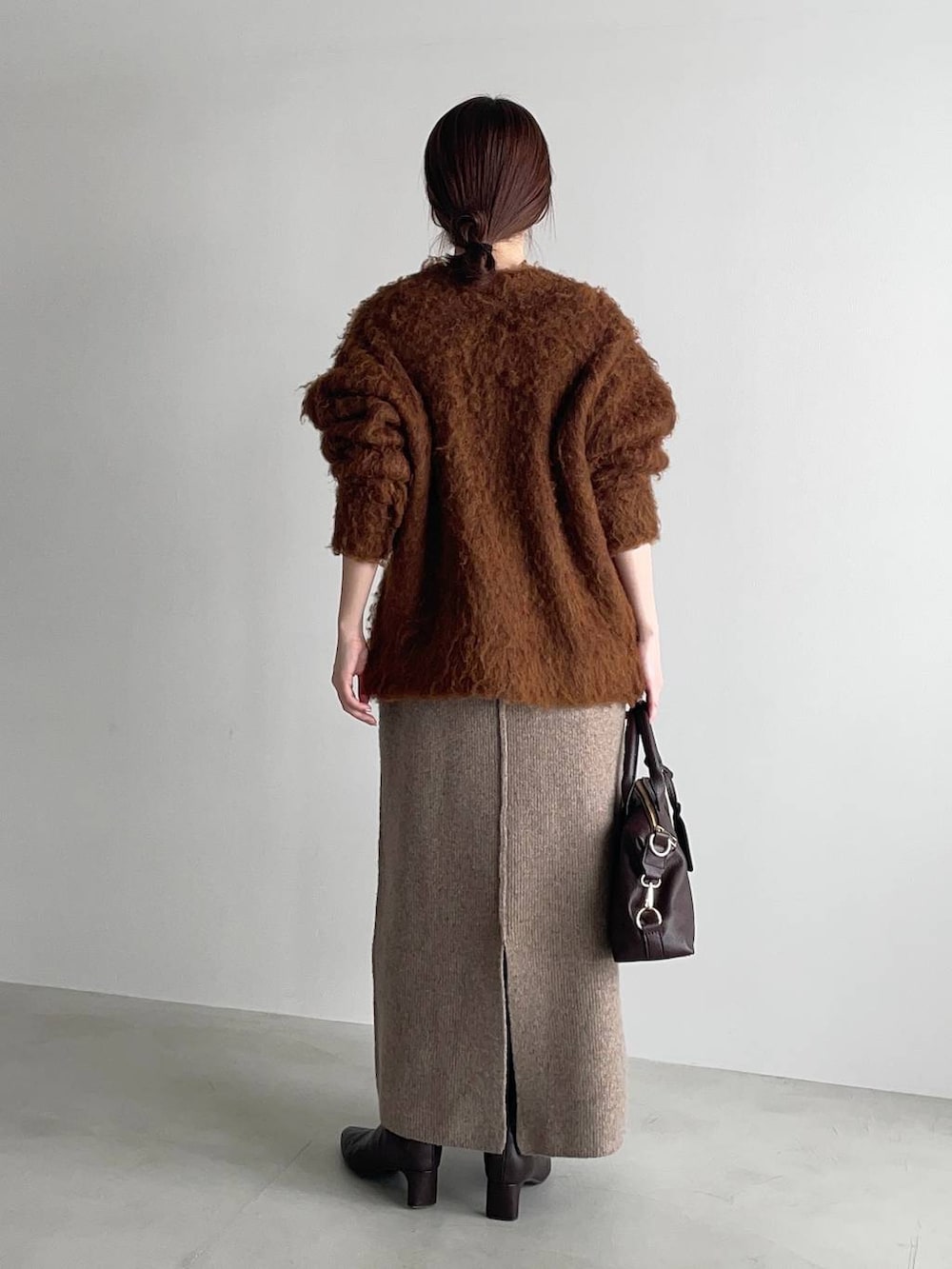 ブラウン系のボストンバッグ、ブラウン系のブーツ、ベージュ系のワンピースを着用したレディースの冬コーディネートの2枚目の写真