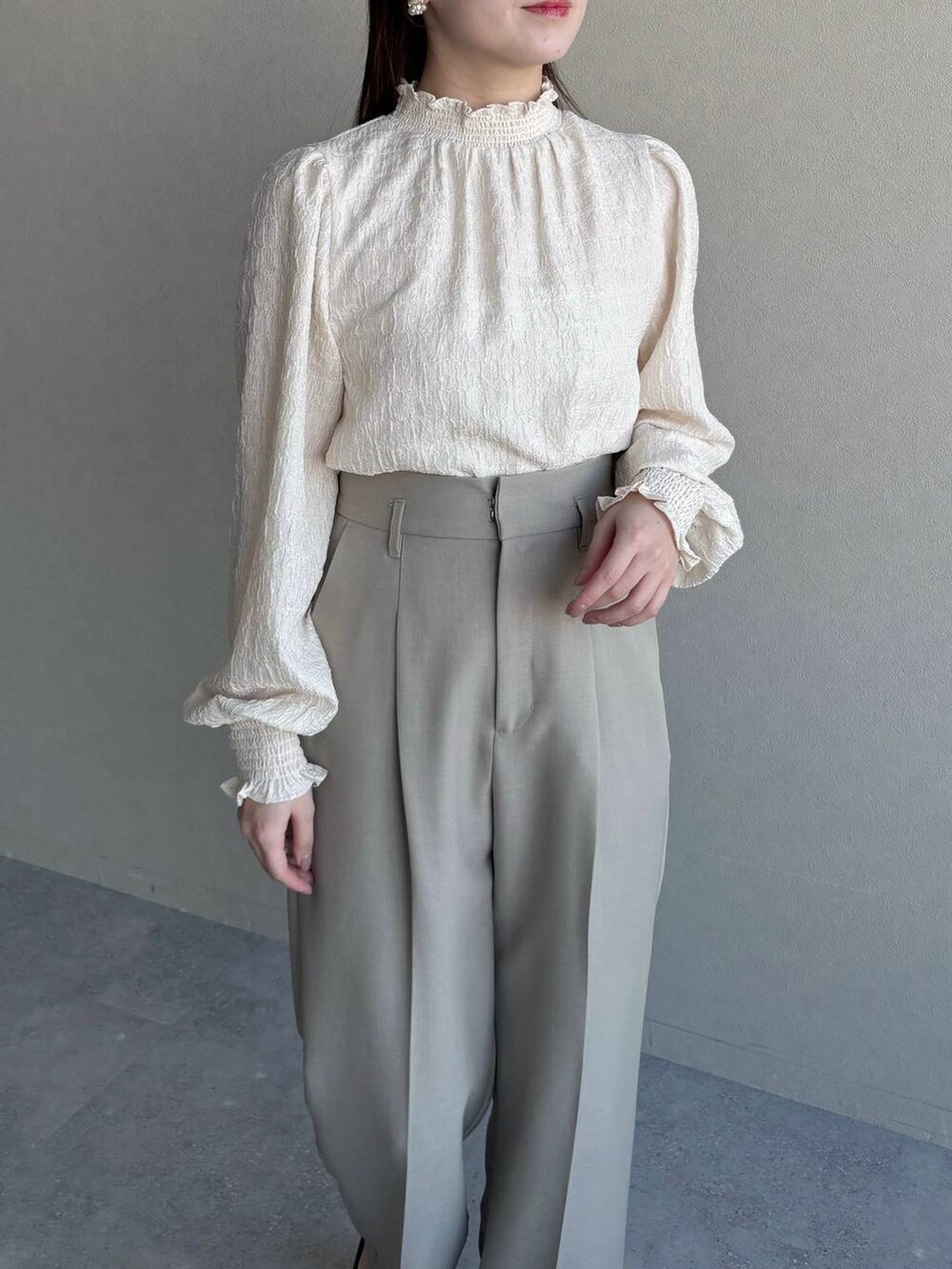 ブラック系のショルダーバッグ、ベージュ系のテーラードジャケット、ベージュ系のスラックスを着用したレディースの冬コーディネートの3枚目の写真