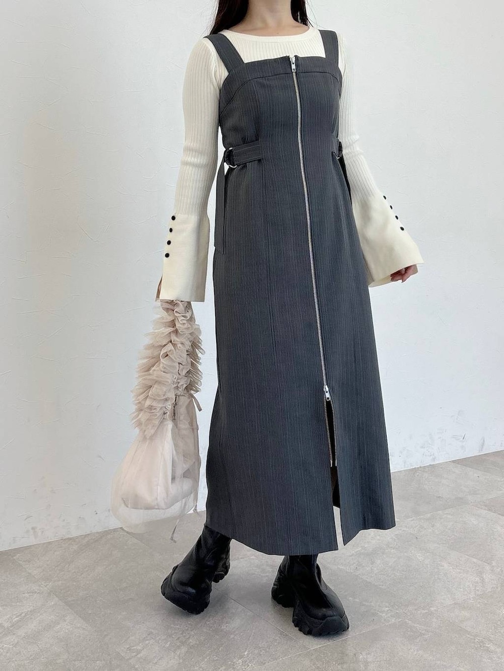 ブラック系のブーツ、ベージュ系のショルダーバッグ、グレー系のジャンパースカートを着用したレディースの冬コーディネートの4枚目の写真