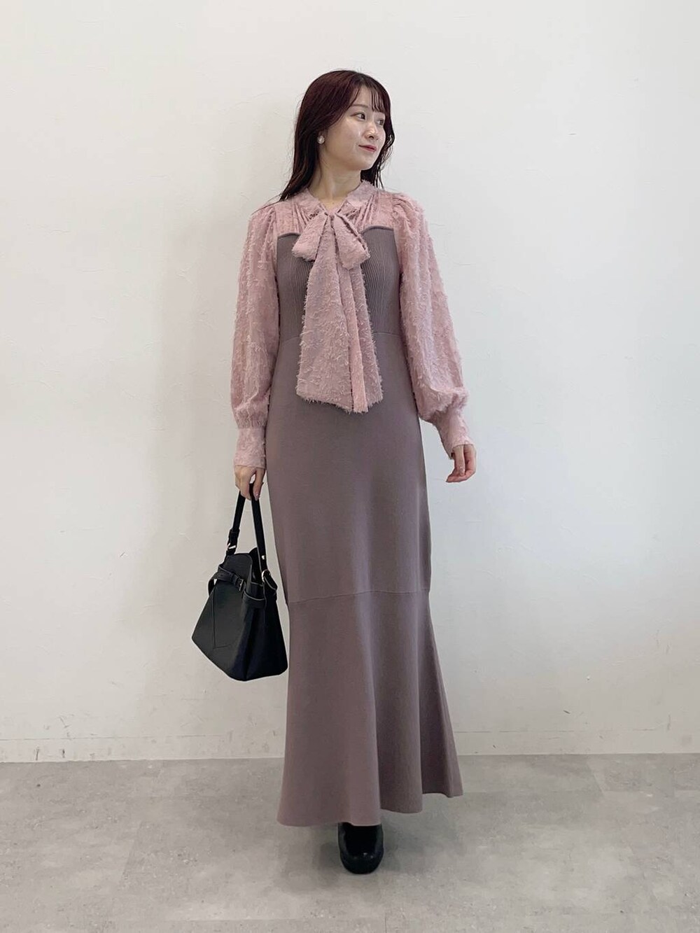 ホワイト系のノーカラーコート、ブラック系のショルダーバッグ、ブラウン系のワンピースを着用したレディースの秋コーディネートの3枚目の写真