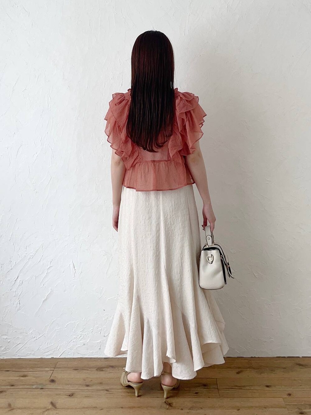 ホワイト系のスカート、ピンク系のシャツ/ブラウス、ゴールド系のパンプスを着用したレディースの春コーディネートの2枚目の写真