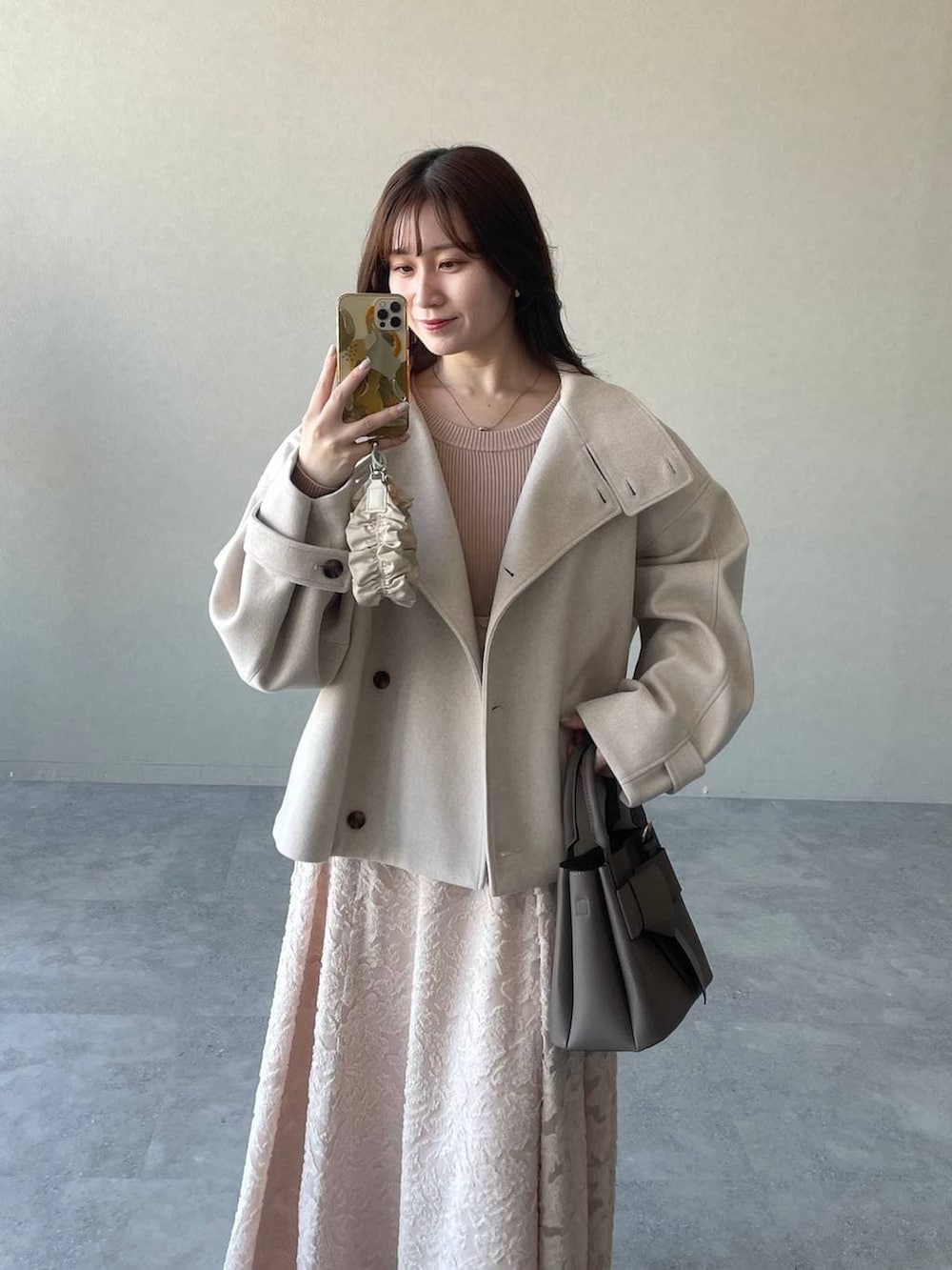 ホワイト系のピーコート、ベージュ系のショルダーバッグ、ブラウン系のブーツを着用したレディースの冬コーディネートの3枚目の写真