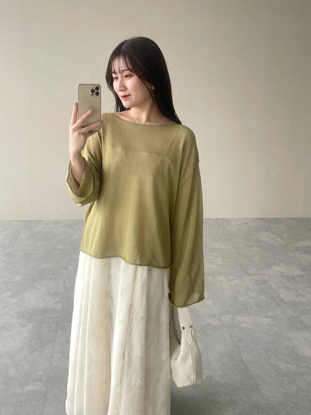 グリーン系のニット/セーター、シルバー系のバレエシューズ、ホワイト系のワンピースを着用したレディースの春コーディネートの3枚目の写真