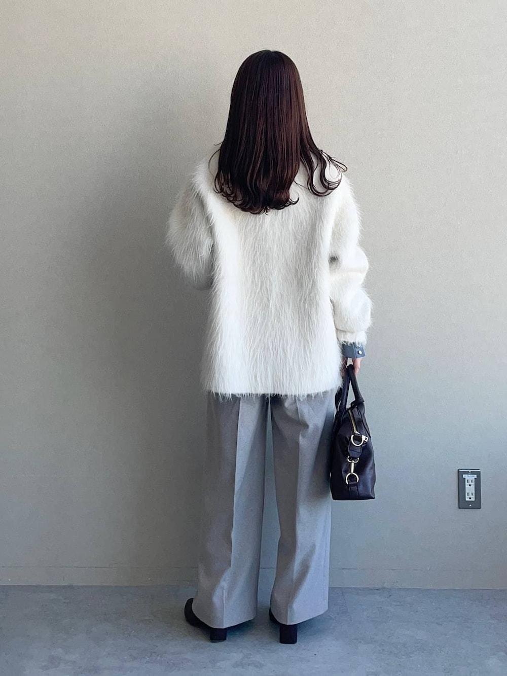 ブラウン系のボストンバッグ、ブラウン系のブーツ、ブルー系のニット/セーターを着用したレディースの冬コーディネートの2枚目の写真