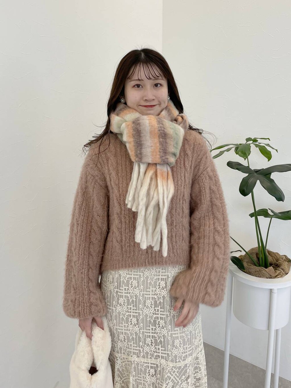 グレー系のブーツ、ホワイト系のスカート、ホワイト系のハンドバッグを着用したレディースの冬コーディネートの3枚目の写真