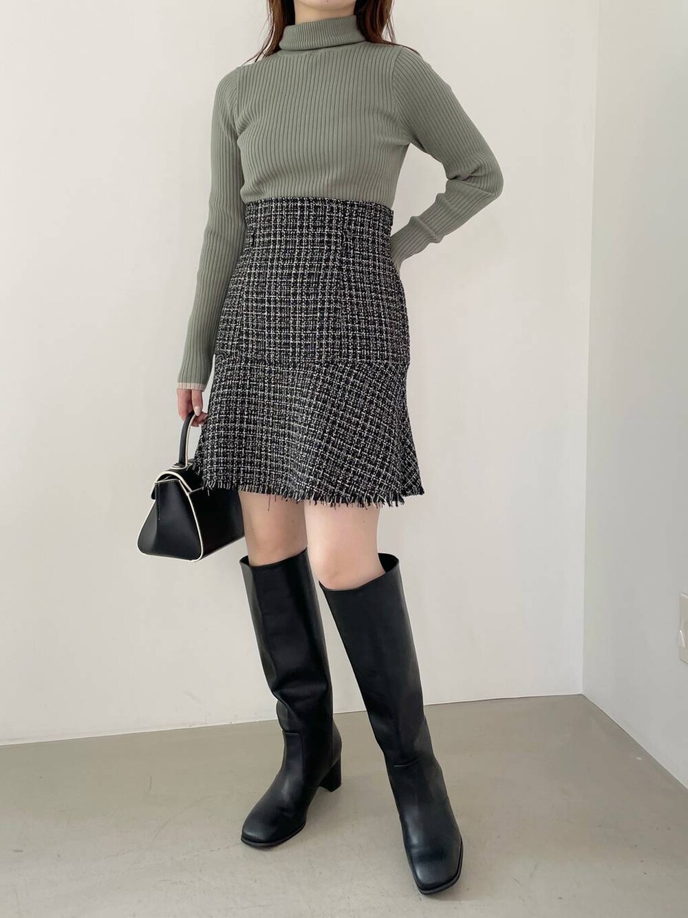 ブラック系のハンドバッグ、ブラック系のブーツ、ブラック系のノーカラージャケットを着用したレディースの秋コーディネートの6枚目の写真