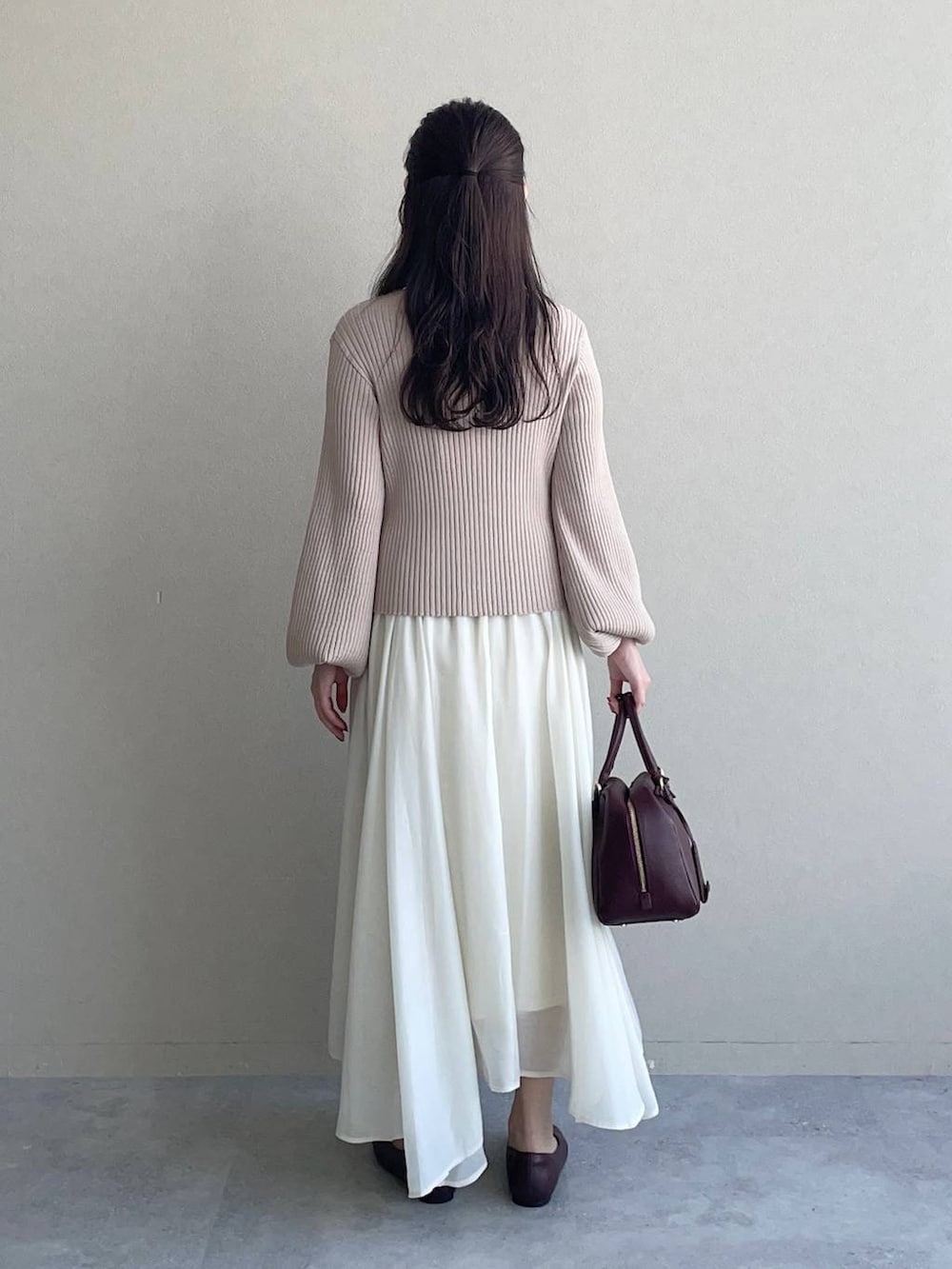 レッド系のハンドバッグ、ピンク系のカーディガン/ボレロ、レッド系のバレエシューズを着用したレディースの秋コーディネートの2枚目の写真