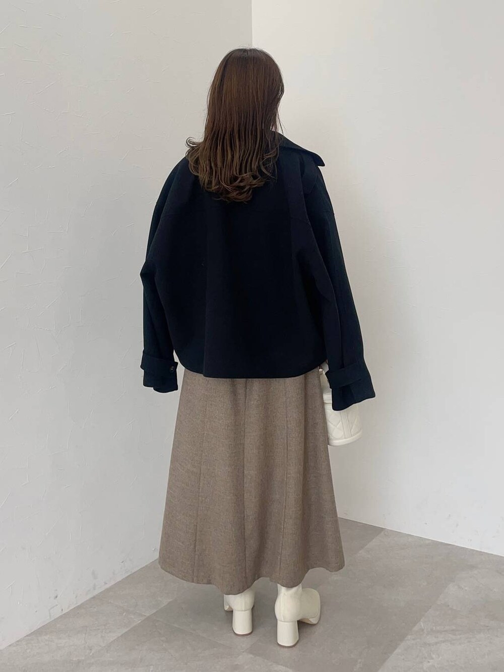 ブラック系のその他アウター、ホワイト系のブーツ、ホワイト系のショルダーバッグを着用したレディースの秋コーディネートの2枚目の写真