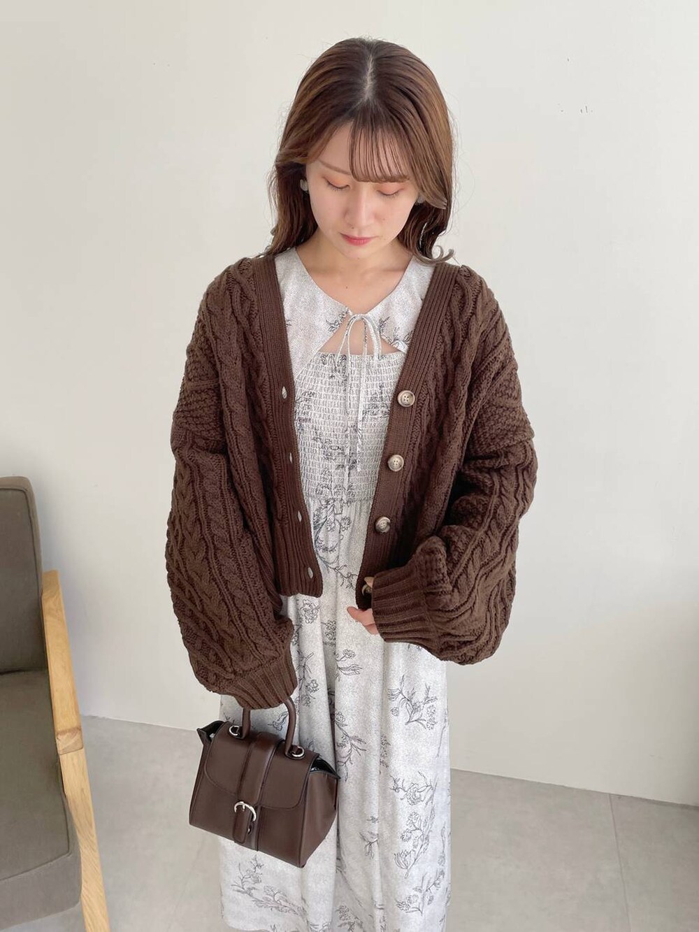 ブラウン系のハンドバッグ、ホワイト系のブーツ、ブラウン系のカーディガン/ボレロを着用したレディースの秋コーディネートの3枚目の写真