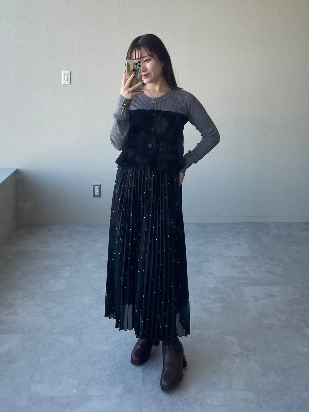 ホワイト系のチェスターコート、ブラウン系のブーツ、グレー系のニット/セーターを着用したレディースの冬コーディネートの3枚目の写真