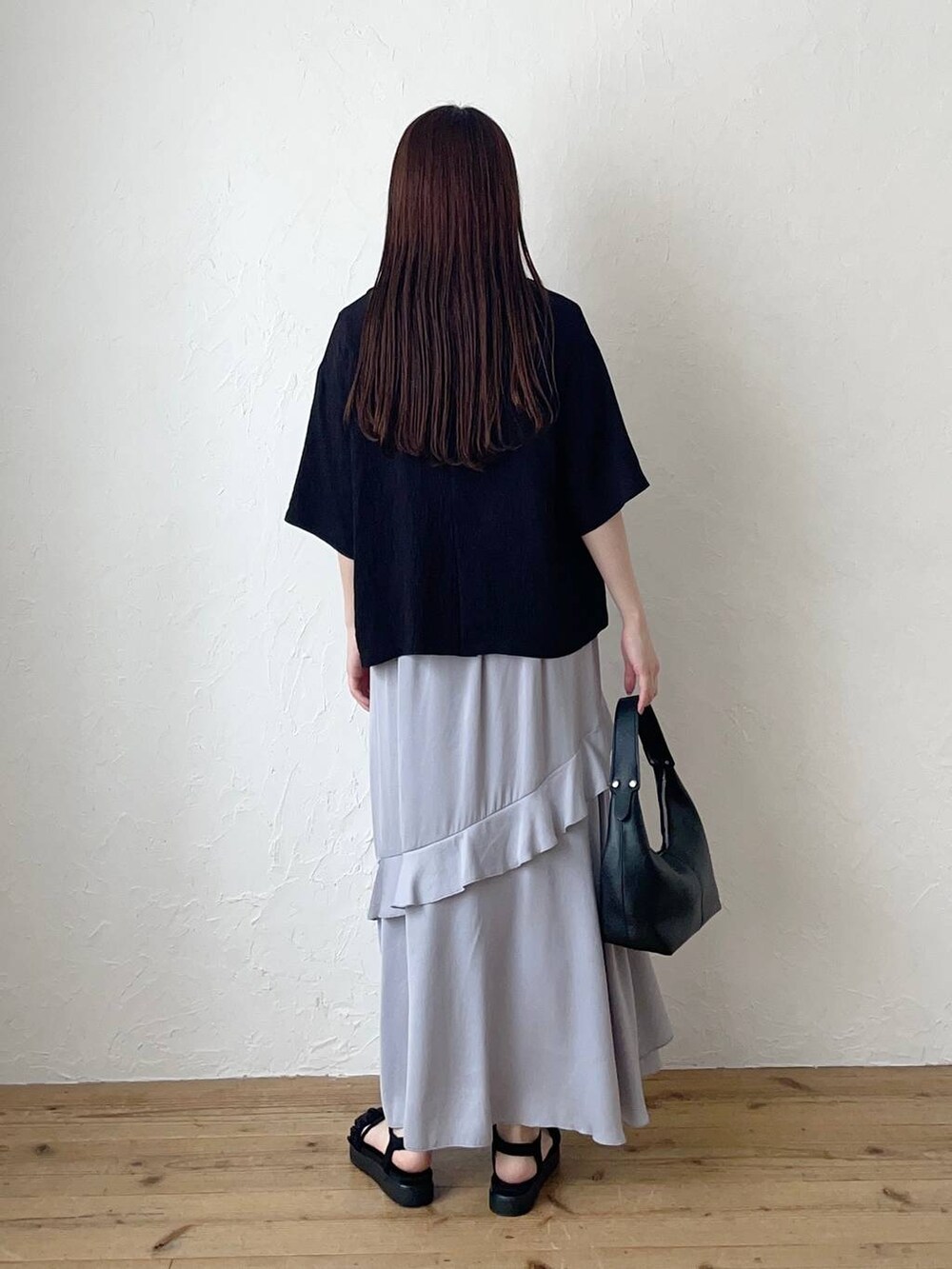 ブラック系のサンダル、グレー系のスカート、ブラック系のショルダーバッグを着用したレディースの夏コーディネートの2枚目の写真