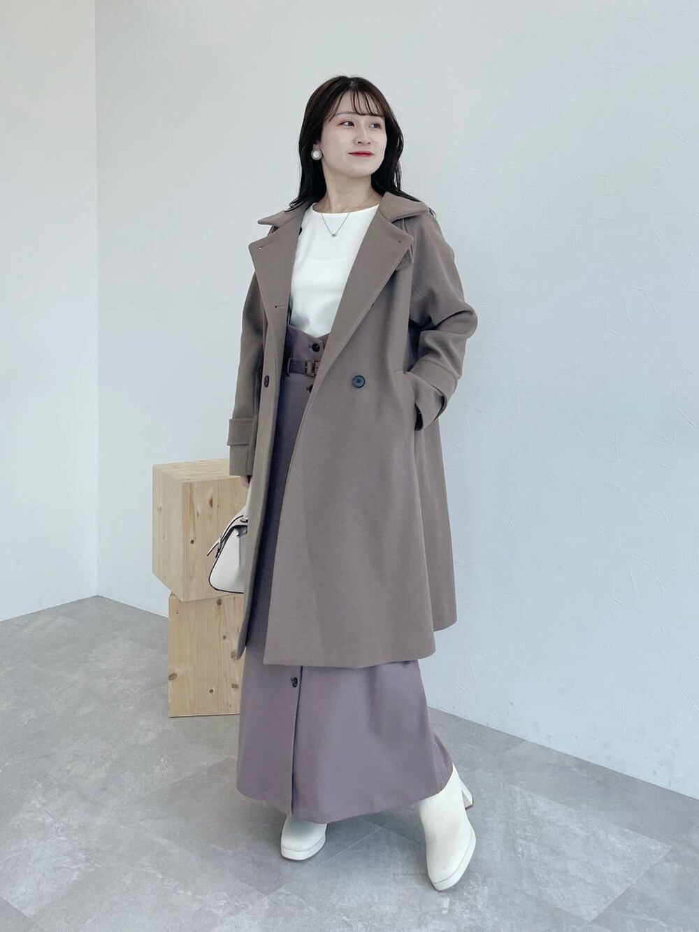 ブラウン系のチェスターコート、ホワイト系のハンドバッグ、ホワイト系のブーツを着用したレディースの夏コーディネートの2枚目の写真