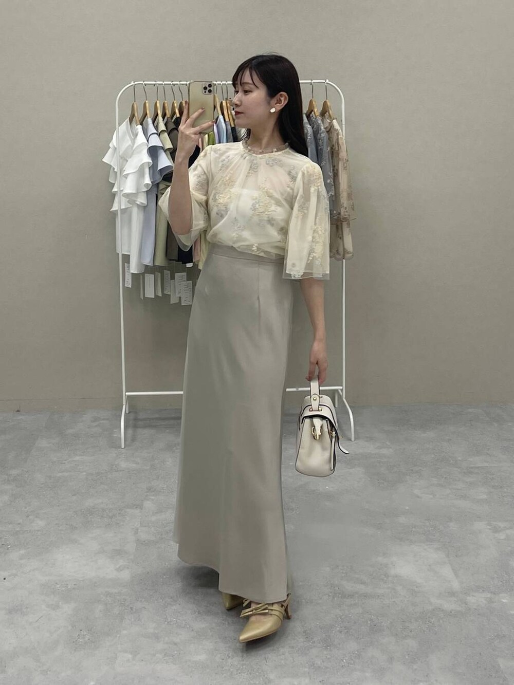 ホワイト系のシャツ/ブラウス、ベージュ系のスカート、ゴールド系のパンプスを着用したレディースの夏コーディネートの2枚目の写真