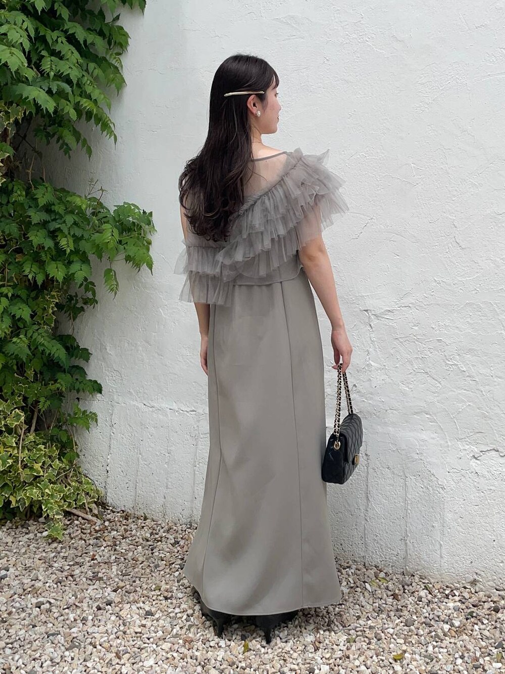 ブラック系のパンプス、グリーン系のドレス、ブラック系のショルダーバッグを着用したレディースの夏コーディネートの2枚目の写真