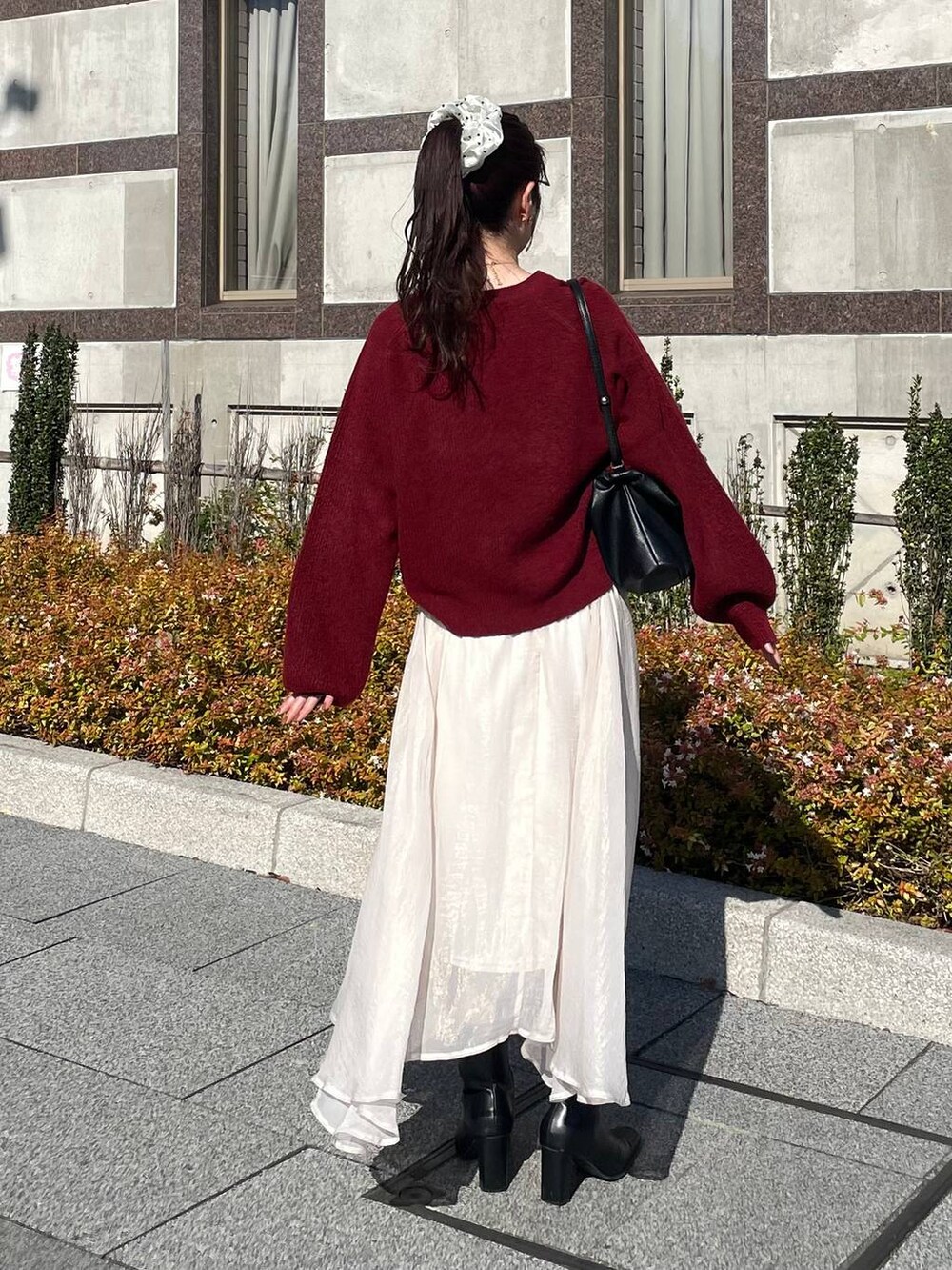 レッド系のニット/セーター、ホワイト系のブルゾン、ホワイト系のスカートを着用したレディースの秋コーディネートの6枚目の写真