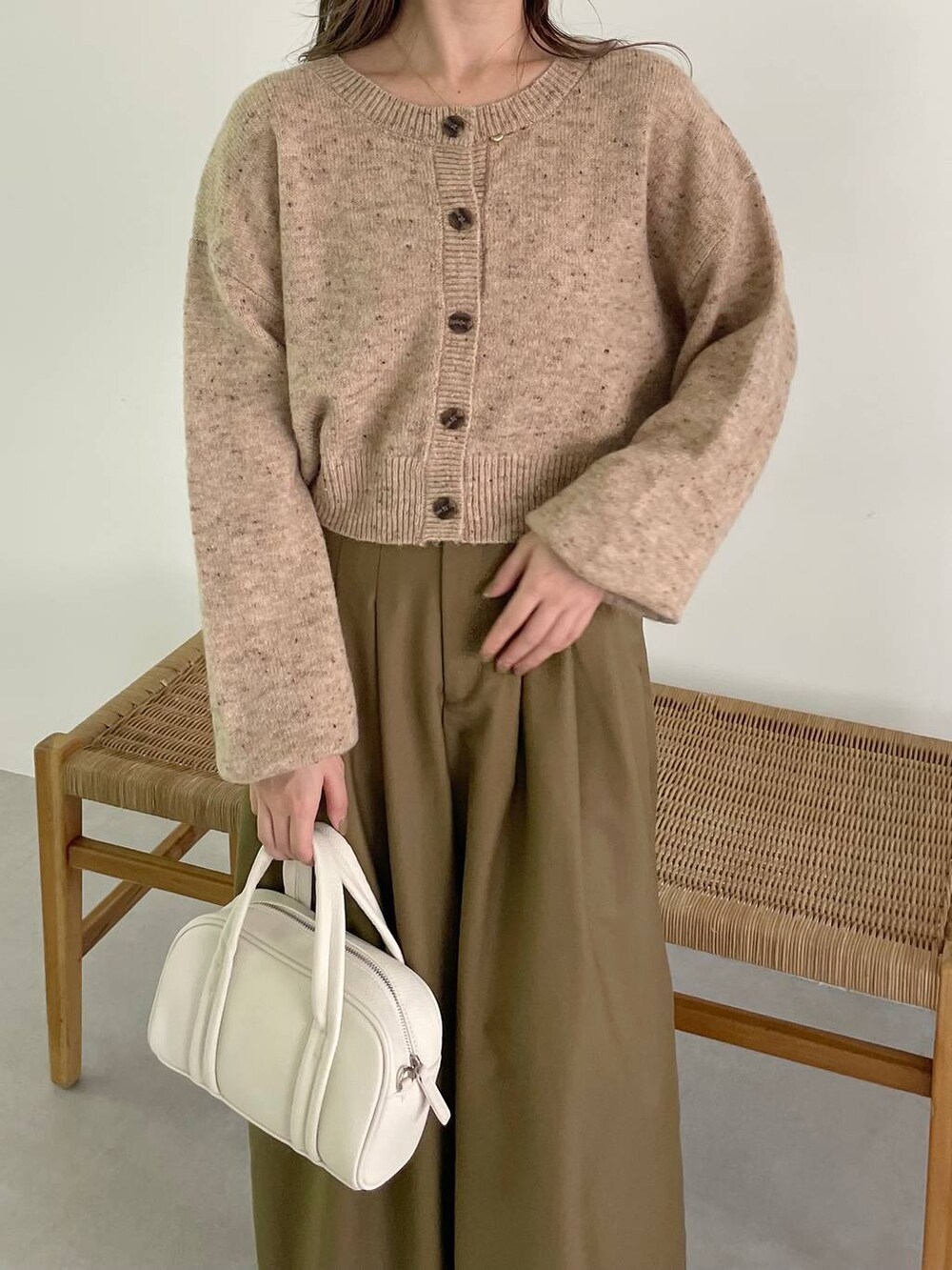 ホワイト系のボストンバッグ、ホワイト系のブーツ、ベージュ系のカーディガン/ボレロを着用したレディースの秋コーディネートの3枚目の写真