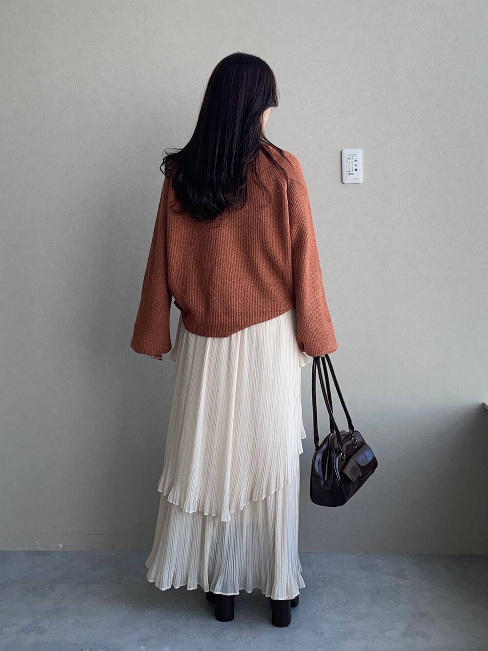 ベージュ系のピーコート、ブラウン系のブーツ、オレンジ系のニット/セーターを着用したレディースの冬コーディネートの4枚目の写真