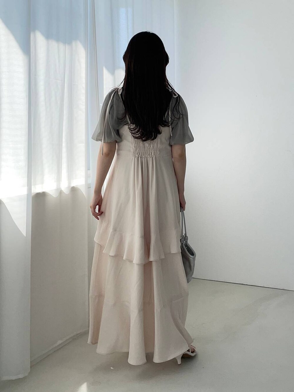 シルバー系のハンドバッグ、ホワイト系のサンダル、ホワイト系のワンピースを着用したレディースの夏コーディネートの2枚目の写真