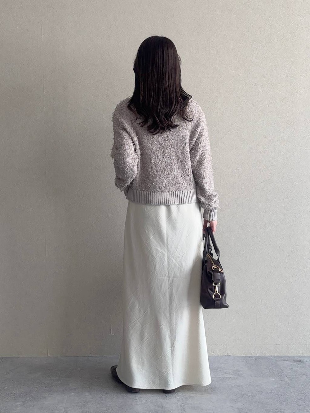 ホワイト系のスカート、ブラウン系のボストンバッグ、ベージュ系のカーディガン/ボレロを着用したレディースの冬コーディネートの2枚目の写真