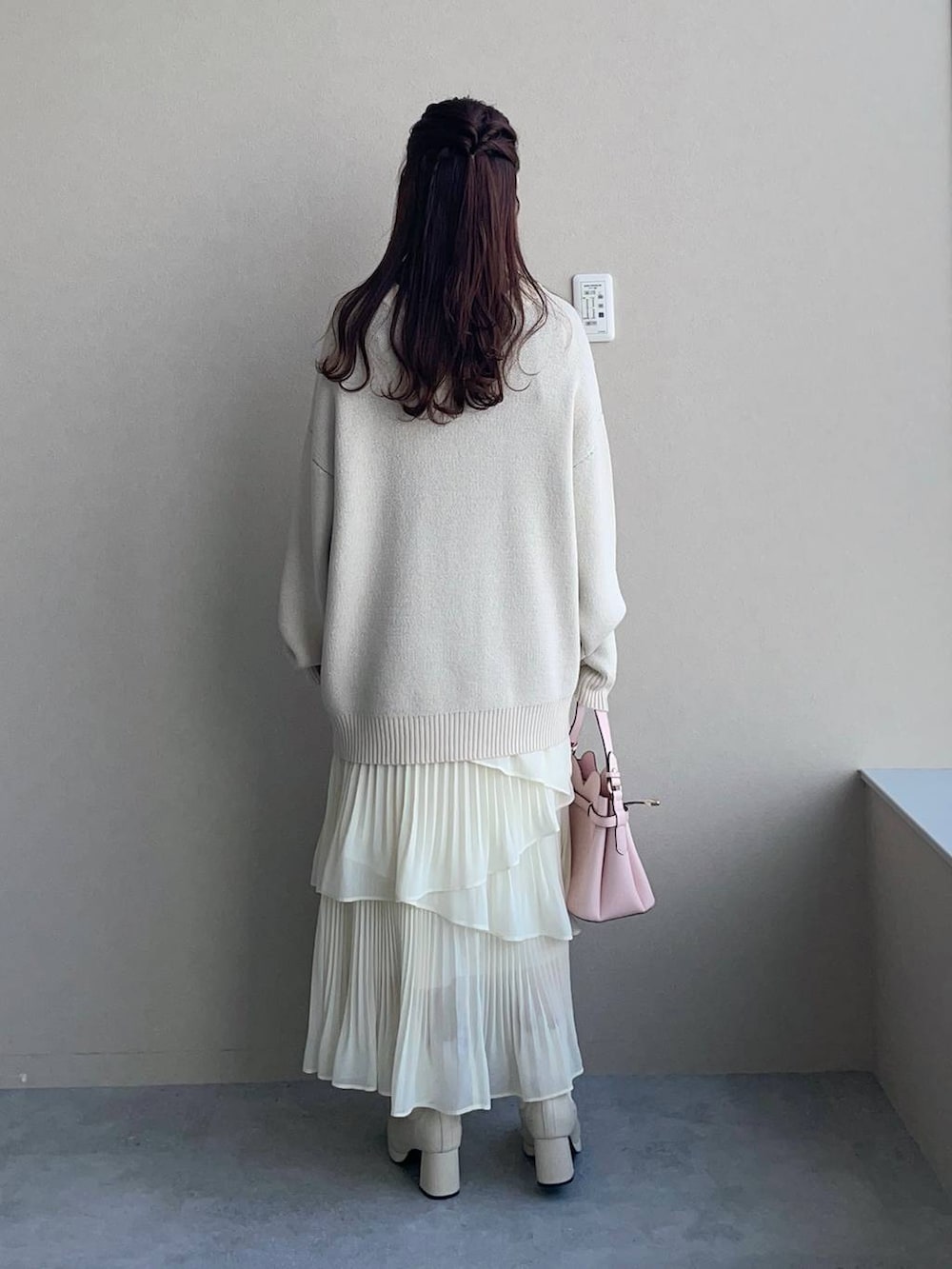 ピンク系のショルダーバッグ、ホワイト系のブーツ、ホワイト系のスカートを着用したレディースの冬コーディネートの2枚目の写真