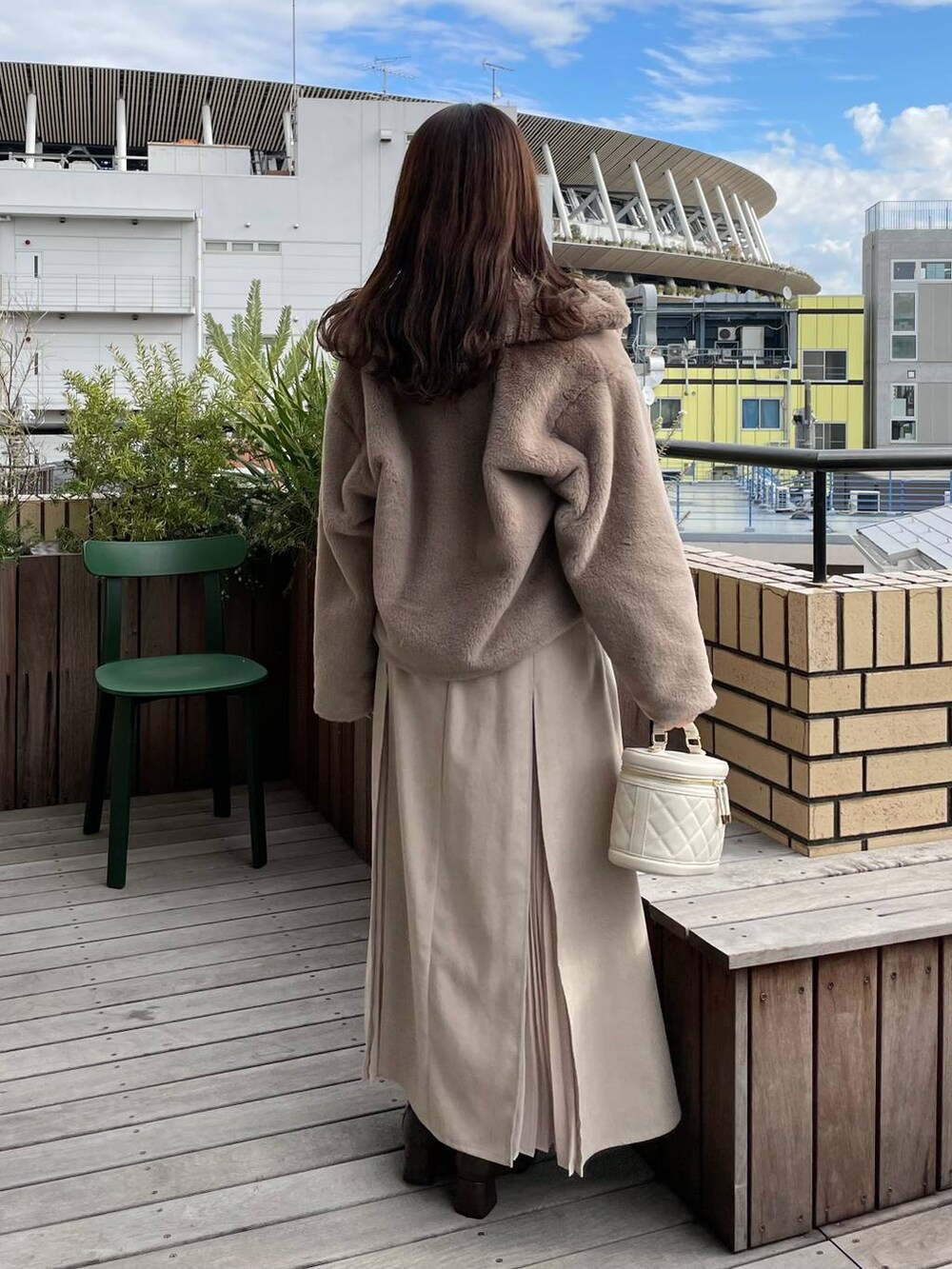 ホワイト系のショルダーバッグ、ブラウン系のブーツ、ベージュ系のブルゾンを着用したレディースの冬コーディネートの2枚目の写真