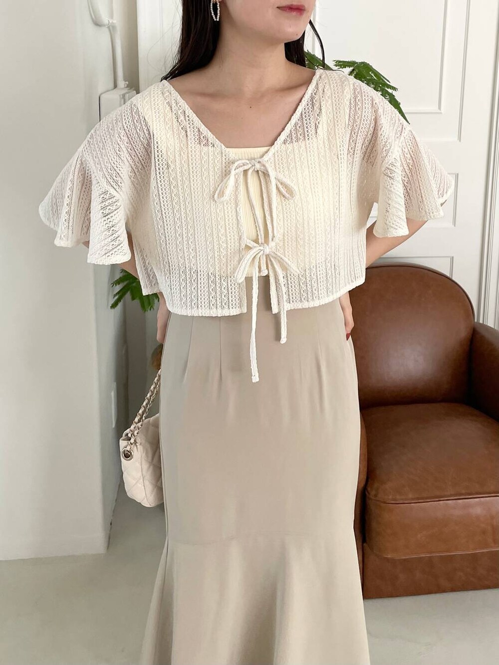 ベージュ系のサンダル、ホワイト系のカーディガン/ボレロ、ホワイト系のショルダーバッグを着用したレディースの夏コーディネートの3枚目の写真