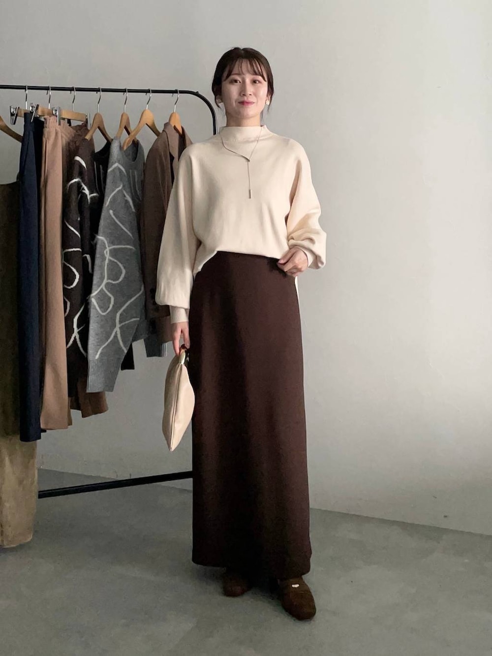 ベージュ系のハンドバッグ、ベージュ系のテーラードジャケット、ブラウン系のスカートを着用したレディースの秋コーディネートの3枚目の写真